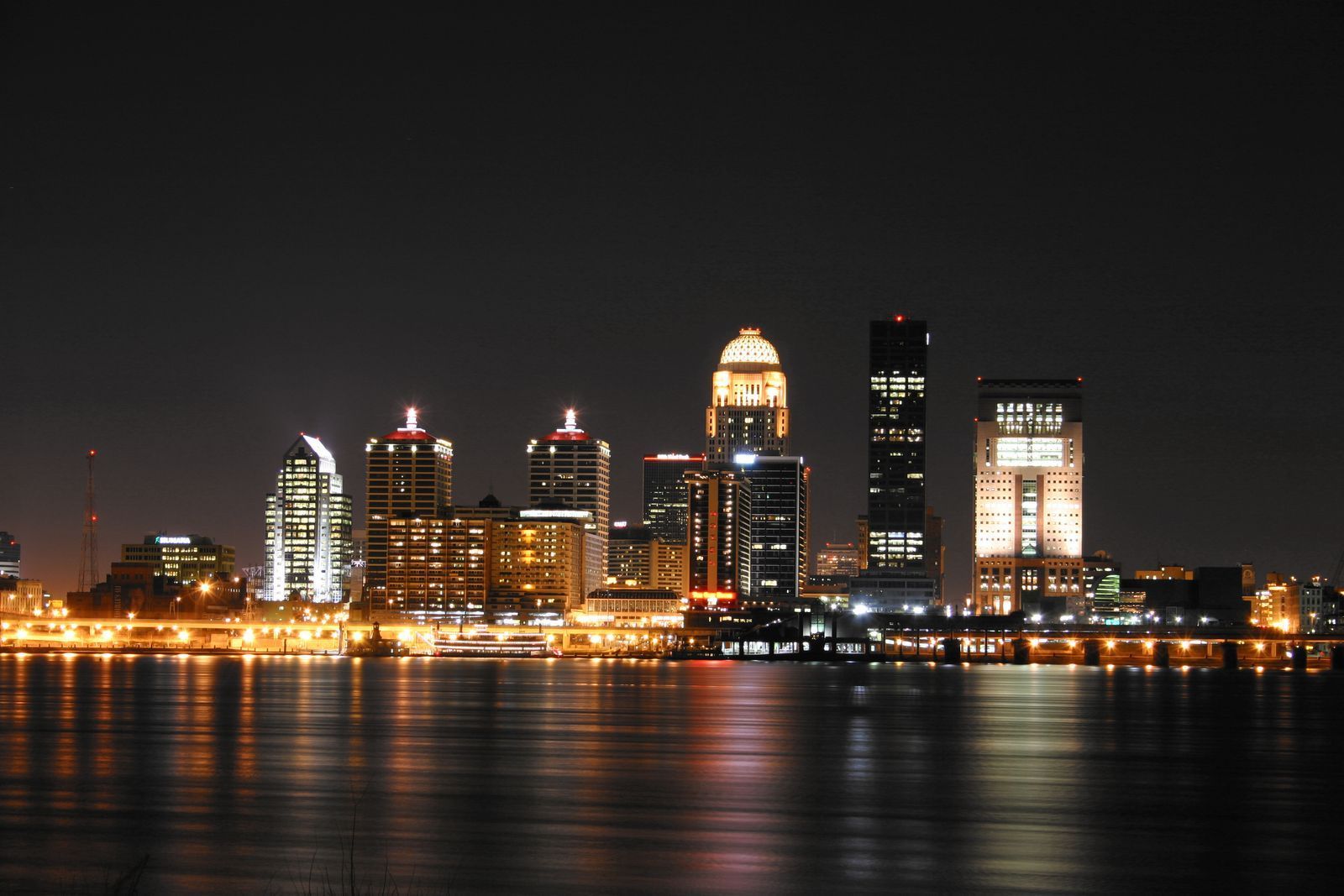 A city skyline at night with a body of water in the foreground