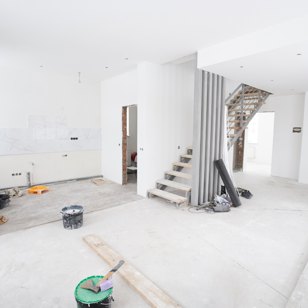 A room with a bucket of paint and a brush on the floor