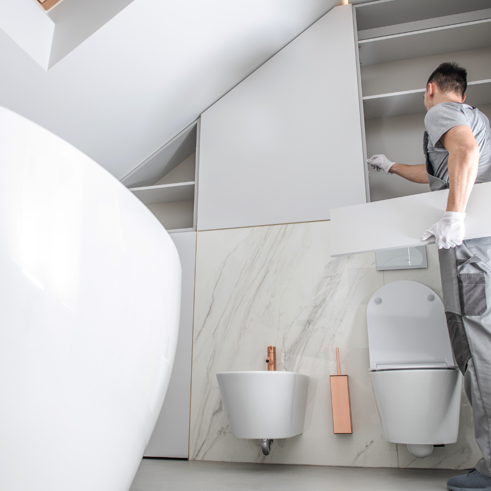 A man is working in a bathroom with a toilet and sink