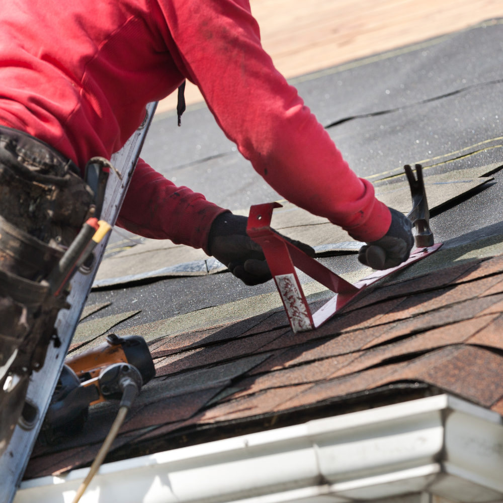 A man in a red shirt is working on a roof