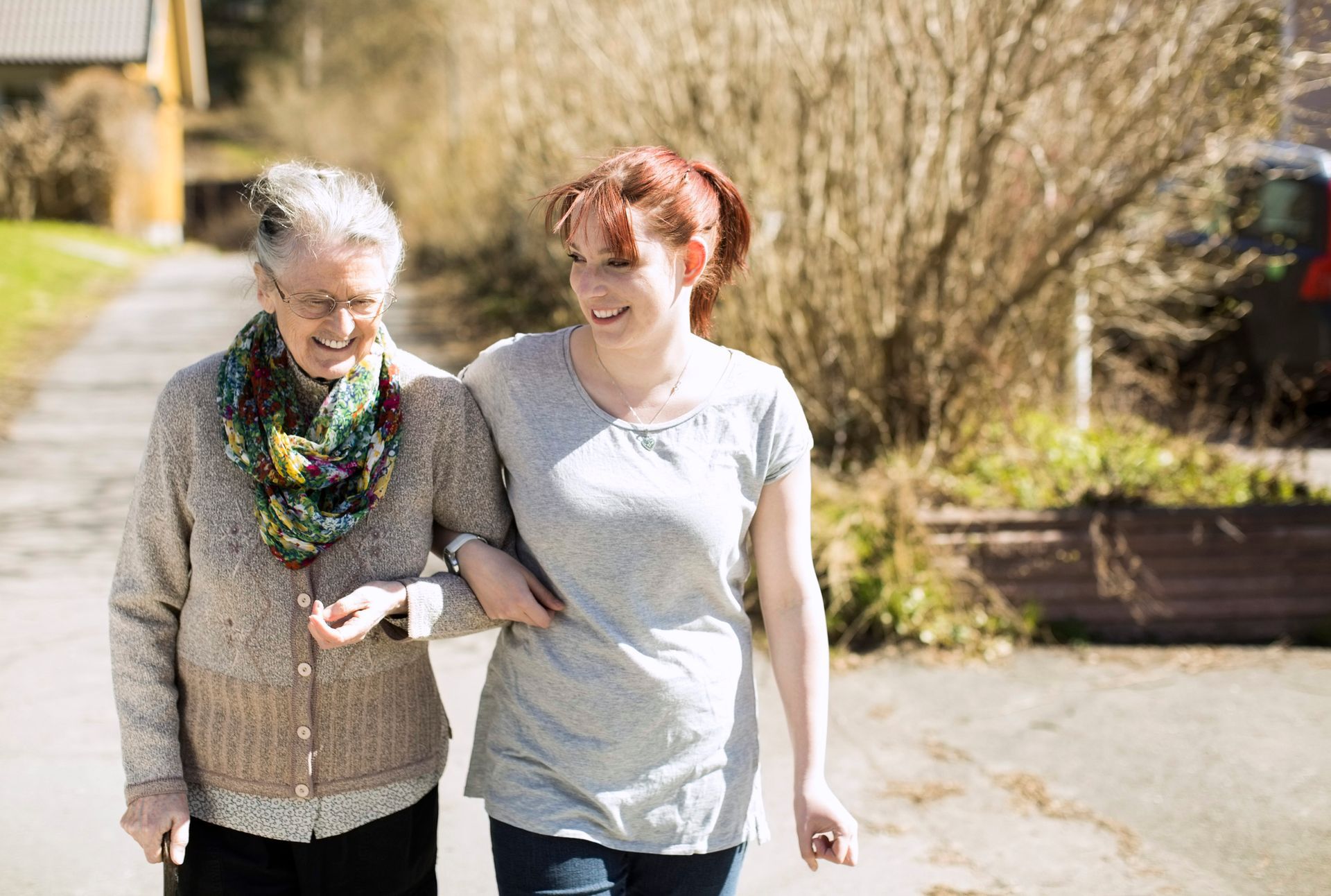 A young woman is helping an older woman walk down the street.