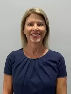 A woman in a blue shirt is smiling for the camera.
