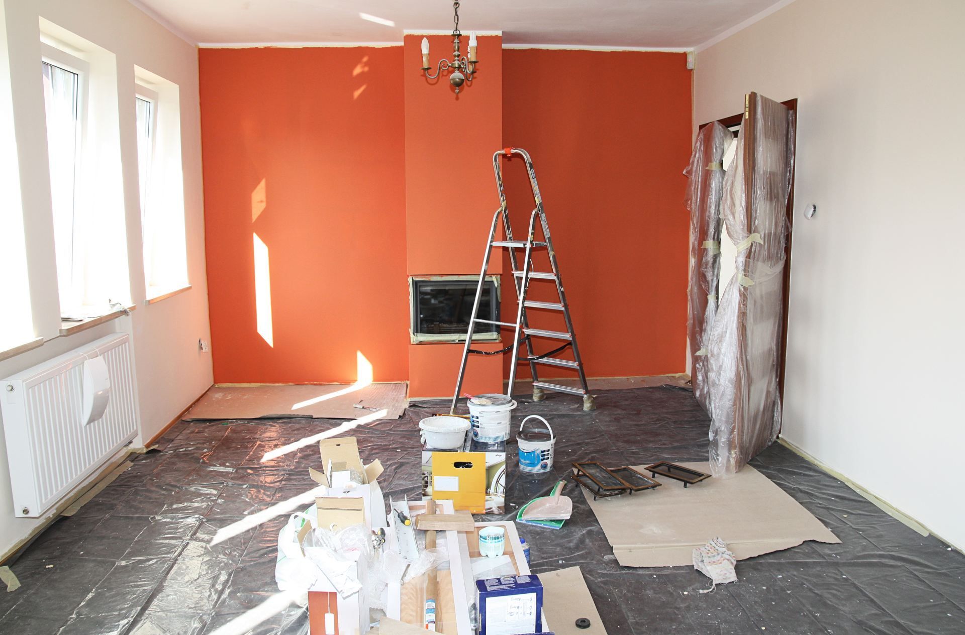 Indoor room being painted orange with a ladder