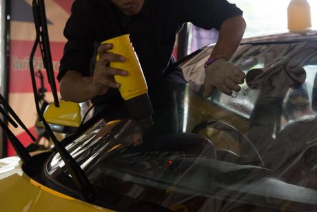 worker applying tinted fill for windshield