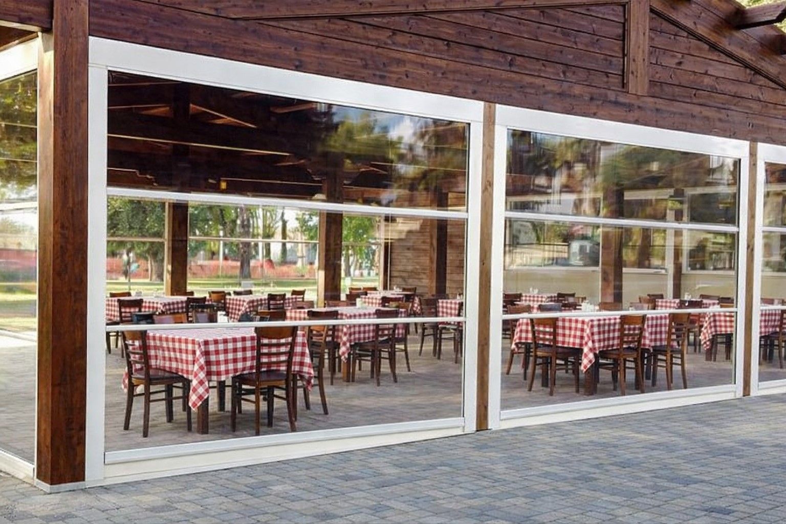 Tavolini all'aperto dietro grandi vetrate con tovaglie a quadri bianchi e rossi