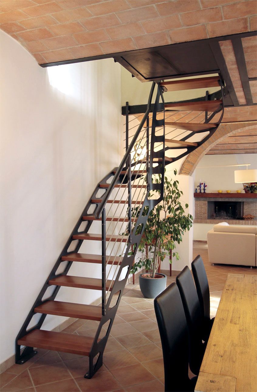 Scala a chiocciola con gradini in legno e ringhiera nera in un luminoso interno open space.