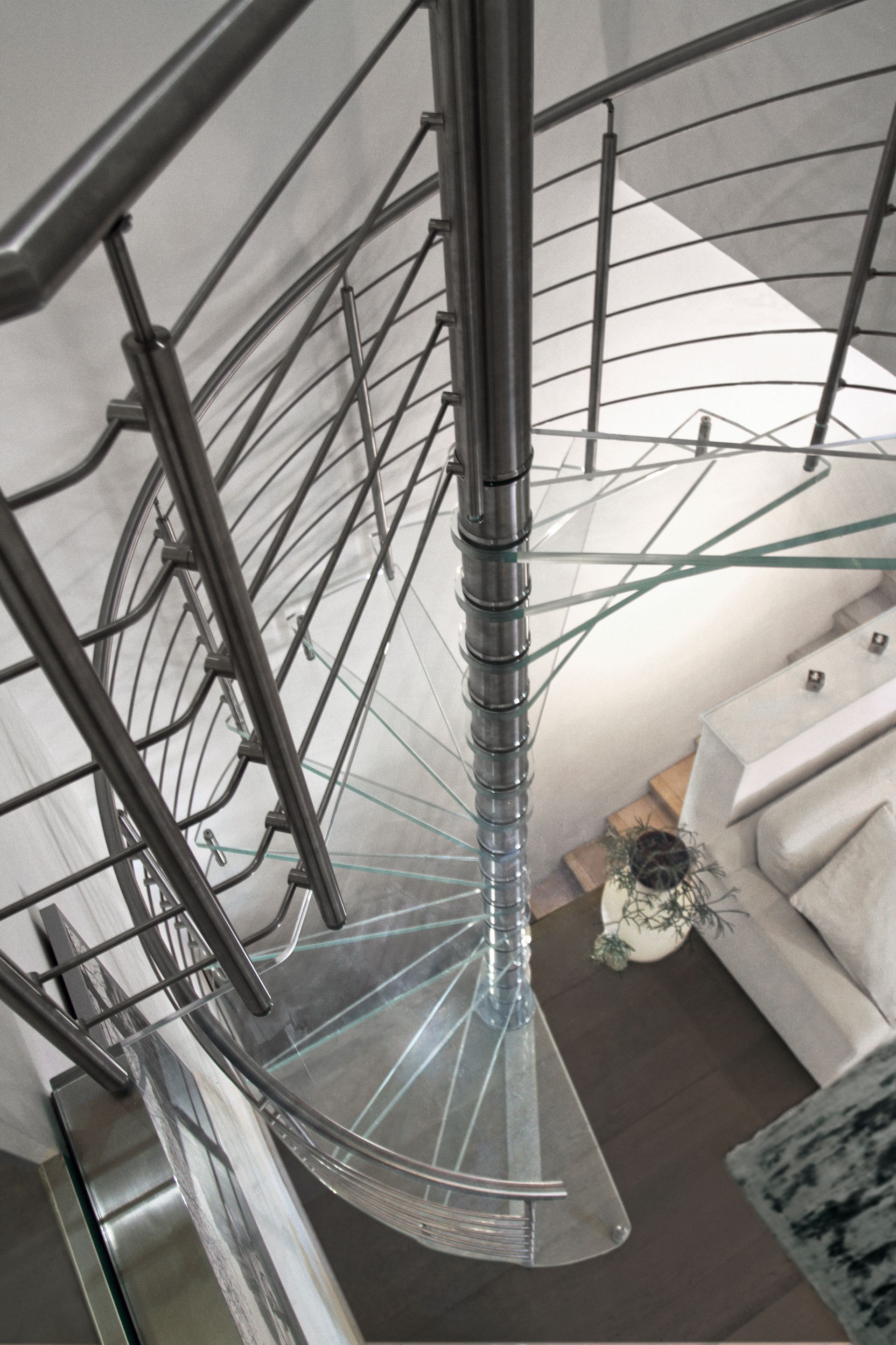Scala a chiocciola moderna con gradini in vetro e ringhiera in metallo vista dall'alto
