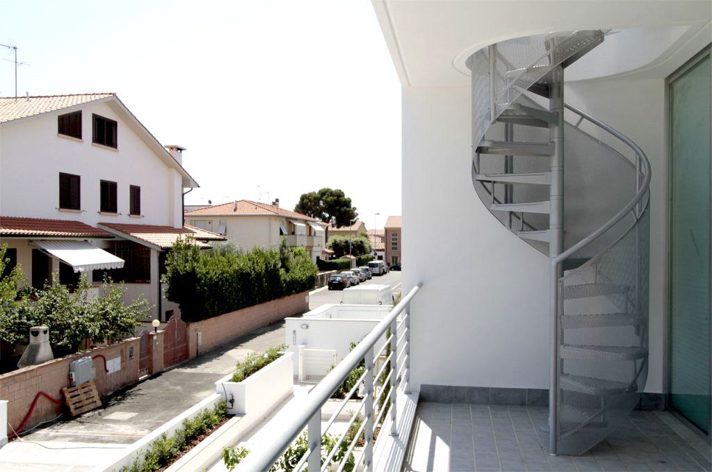 Vista dal balcone su una tranquilla strada residenziale con una scala a chiocciola e case bianche.