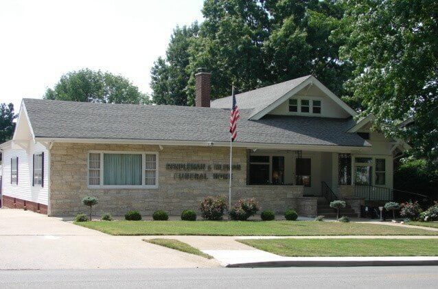 Building with flag, lawn, and text: 