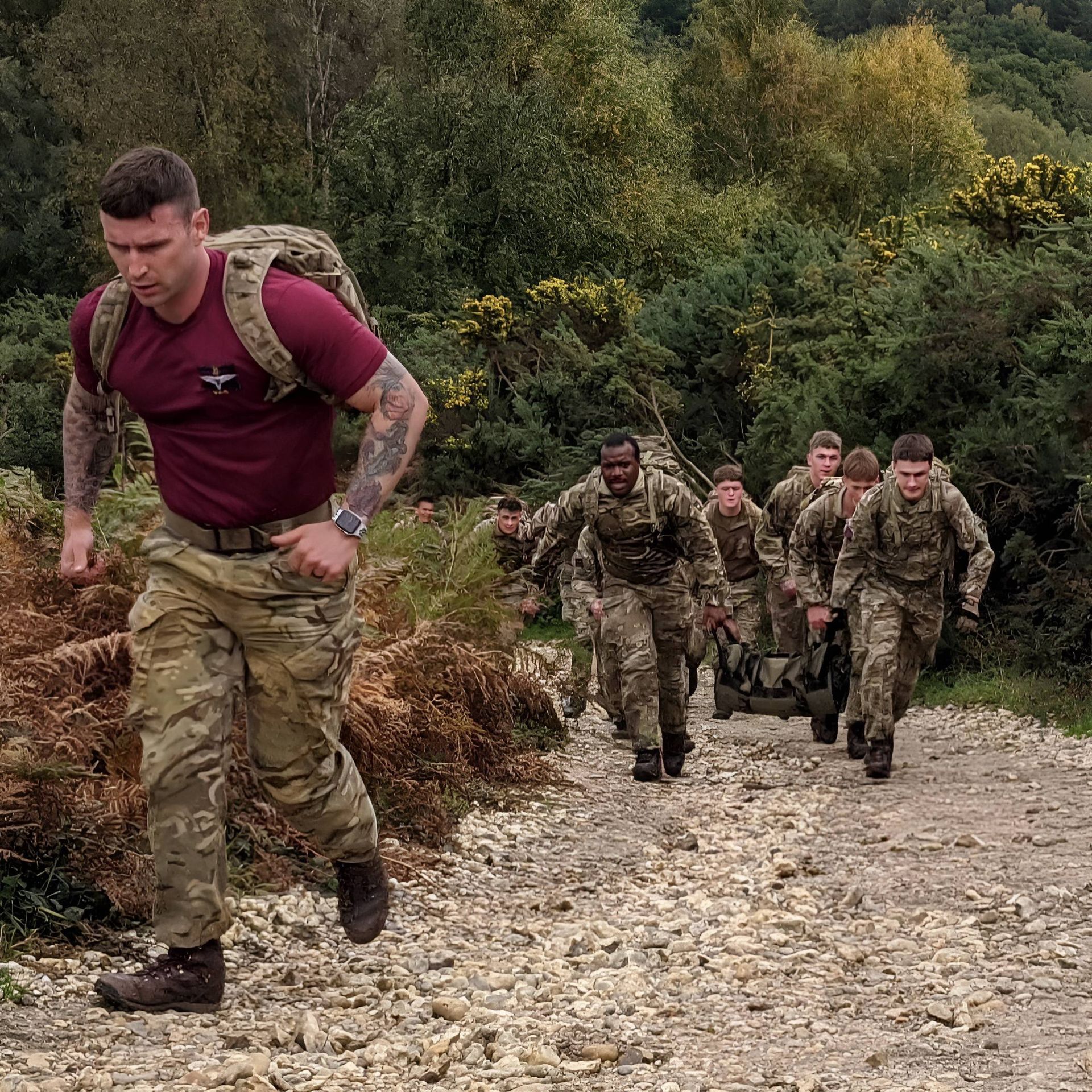 a group of soldiers are walking down a dirt road .