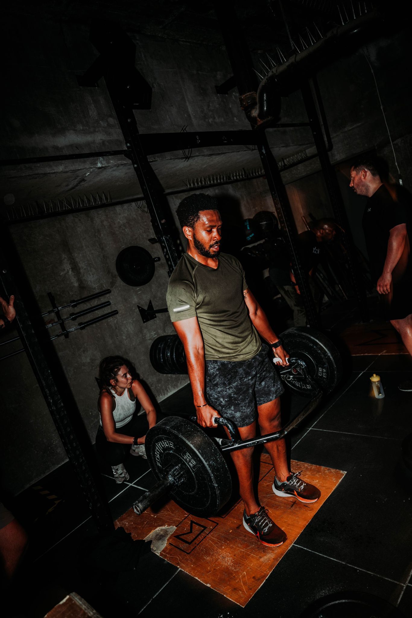 A man is lifting a barbell in a gym.