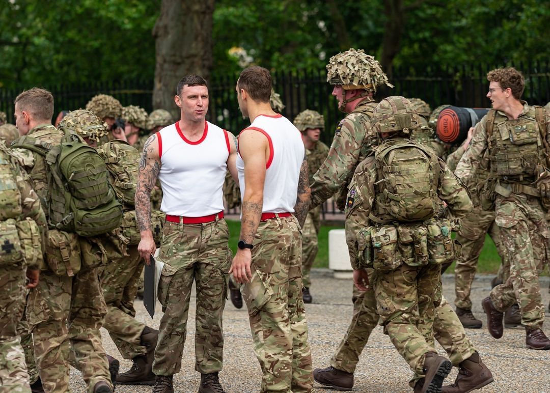 A group of soldiers are walking down a street and talking to each other.