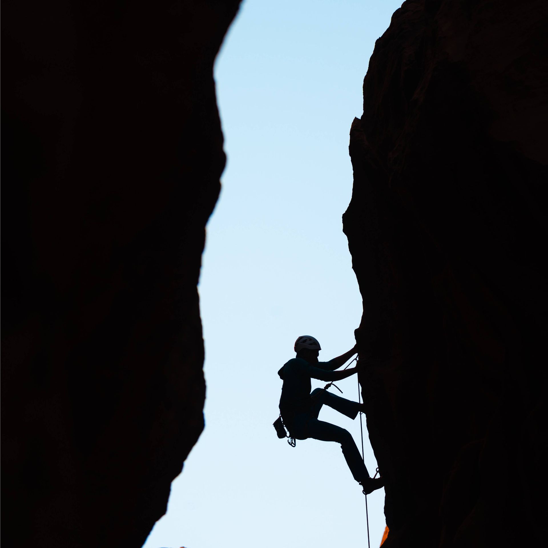 a silhouette of a person climbing a rock wall