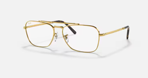 Un paio di occhiali con montatura dorata su una superficie bianca.