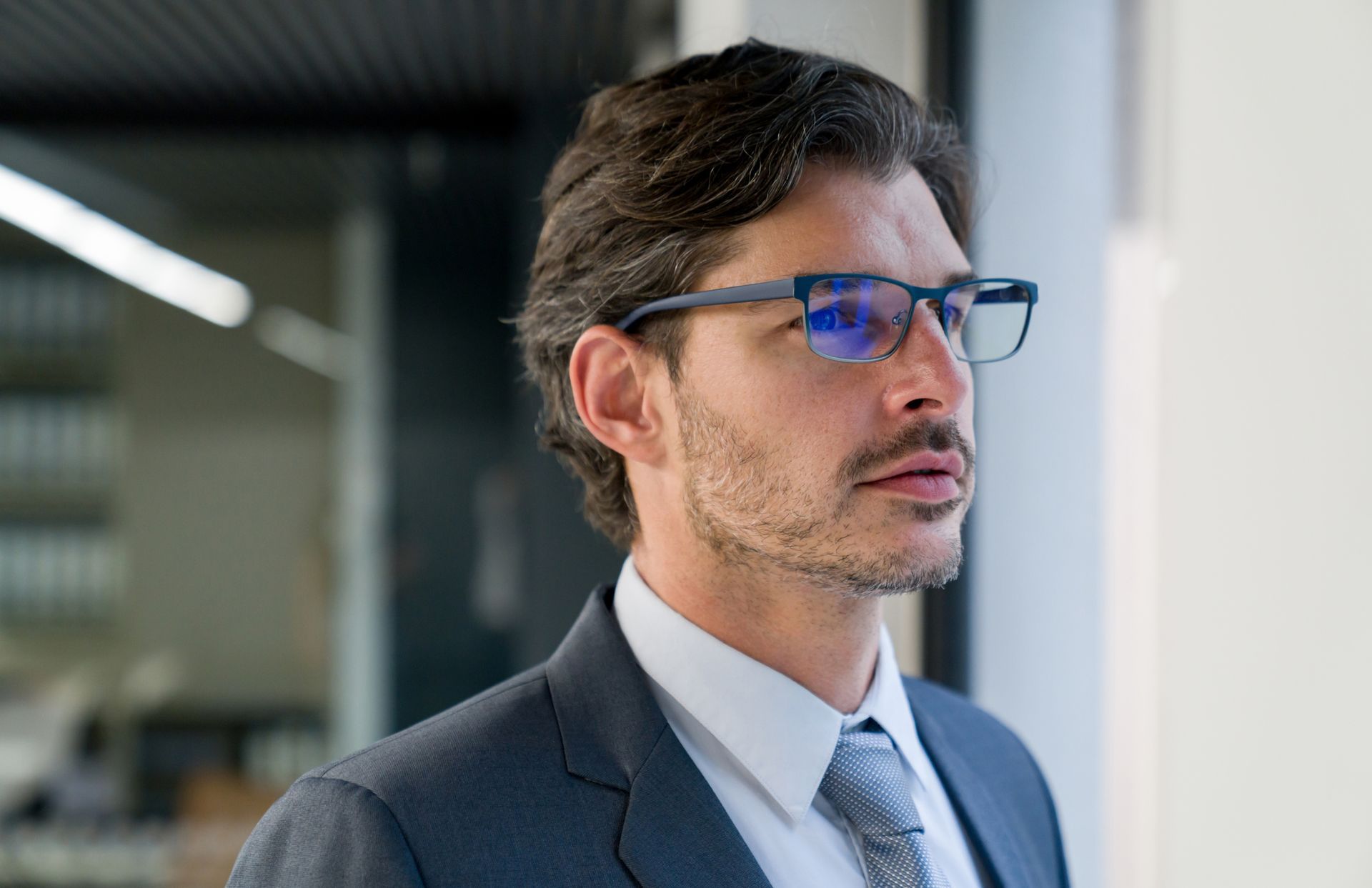 Un uomo in giacca e cravatta indossa gli occhiali.