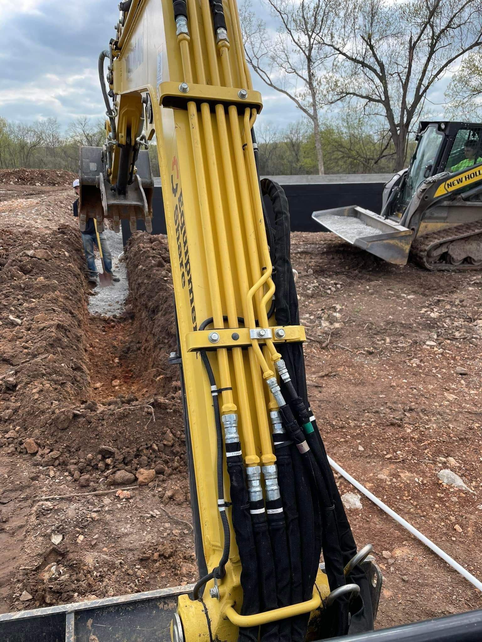 A yellow excavator is digging a hole in the dirt on a construction site.