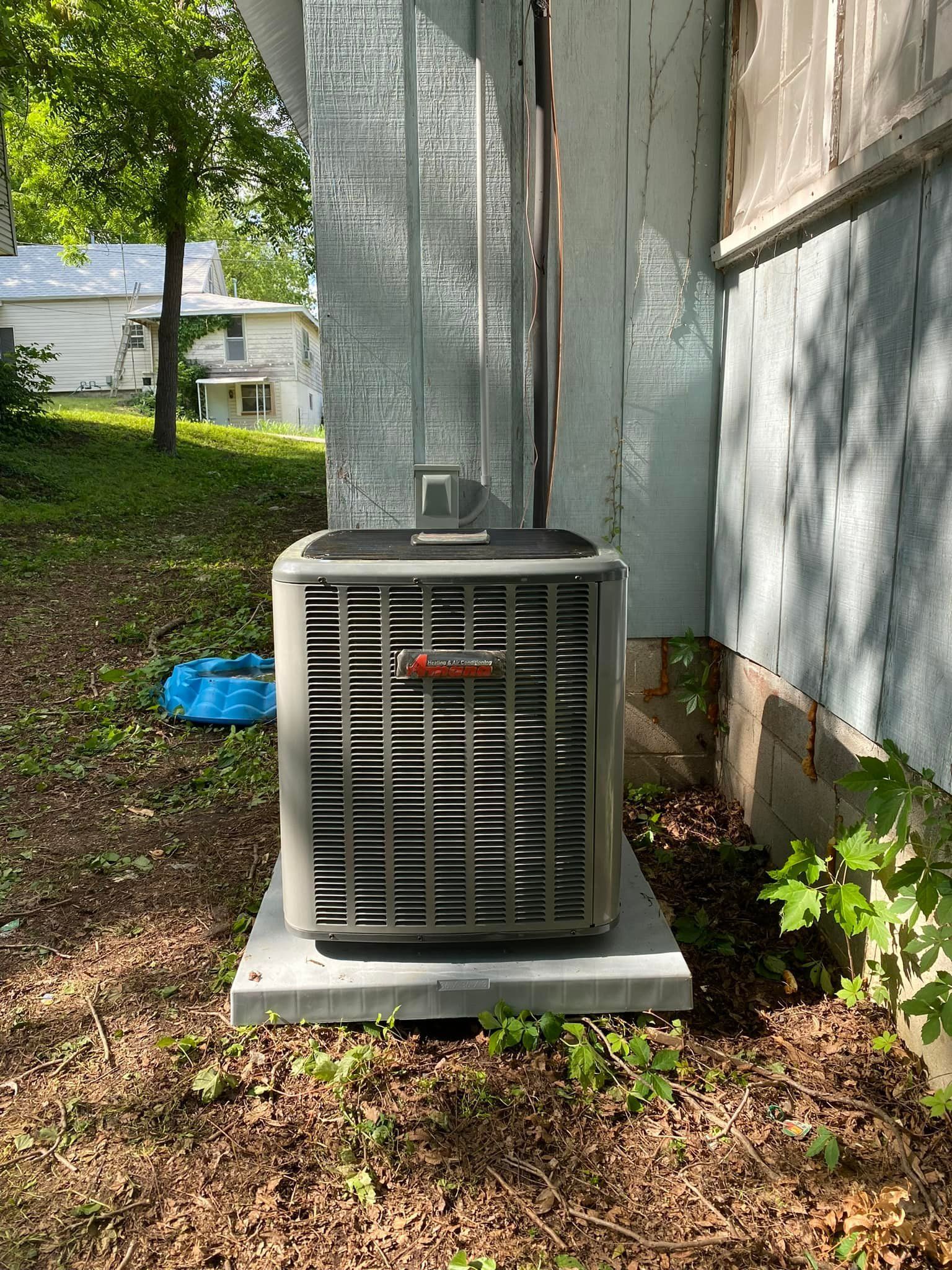 An air conditioner is sitting on the side of a house.