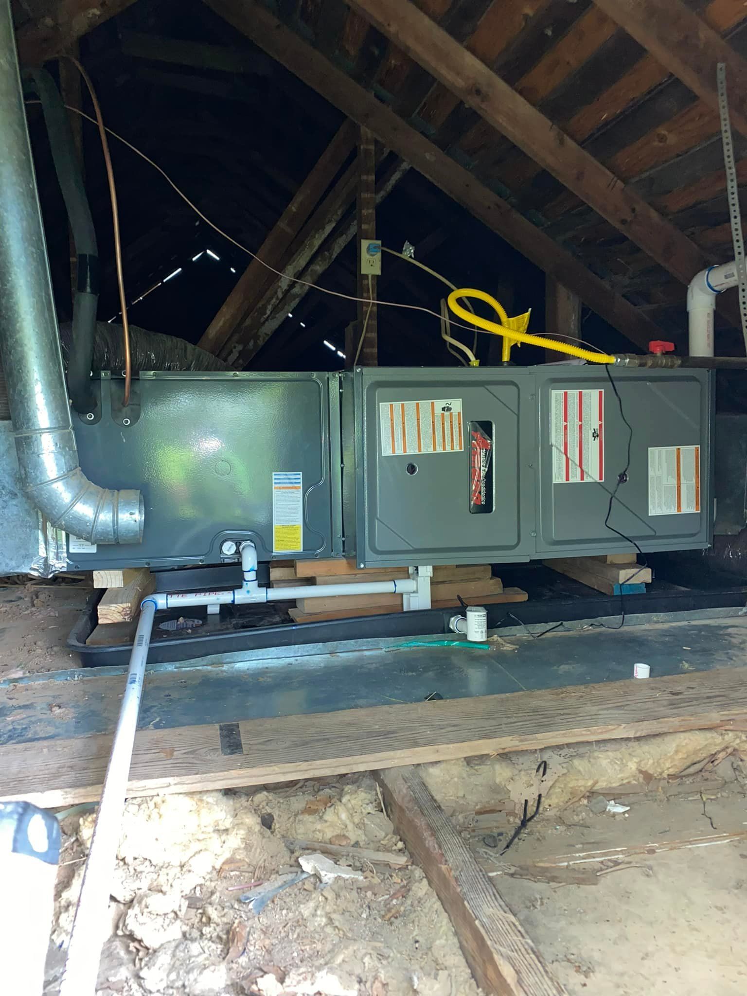 An air conditioner is sitting in the attic of a house.