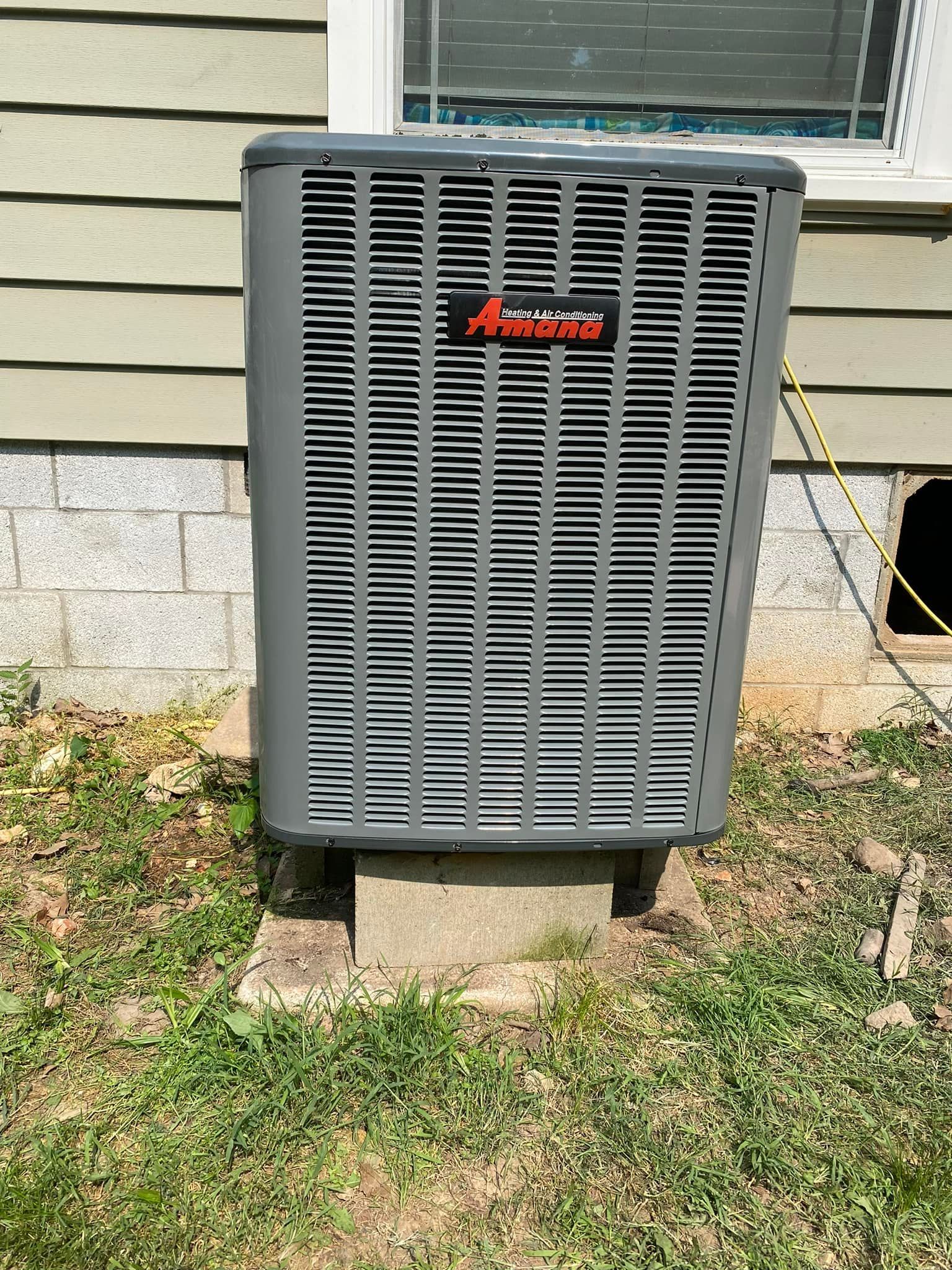 An air conditioner is sitting on the side of a house.