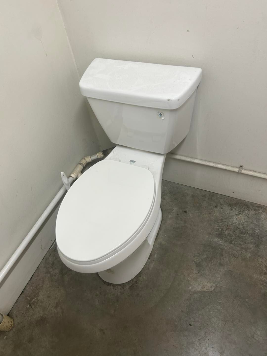 A white toilet in a bathroom with a concrete floor