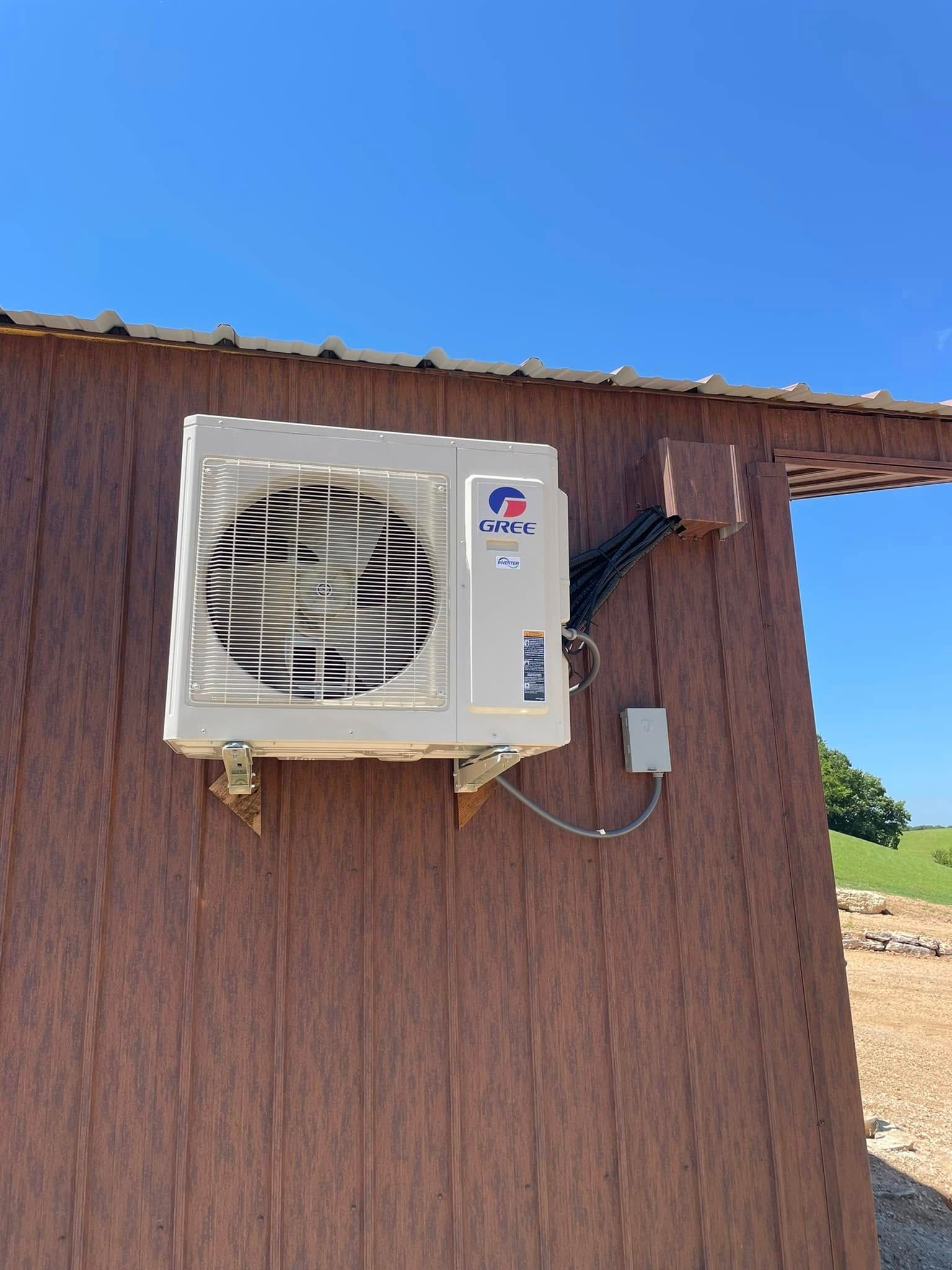 A white air conditioner is mounted on the side of a wooden building.