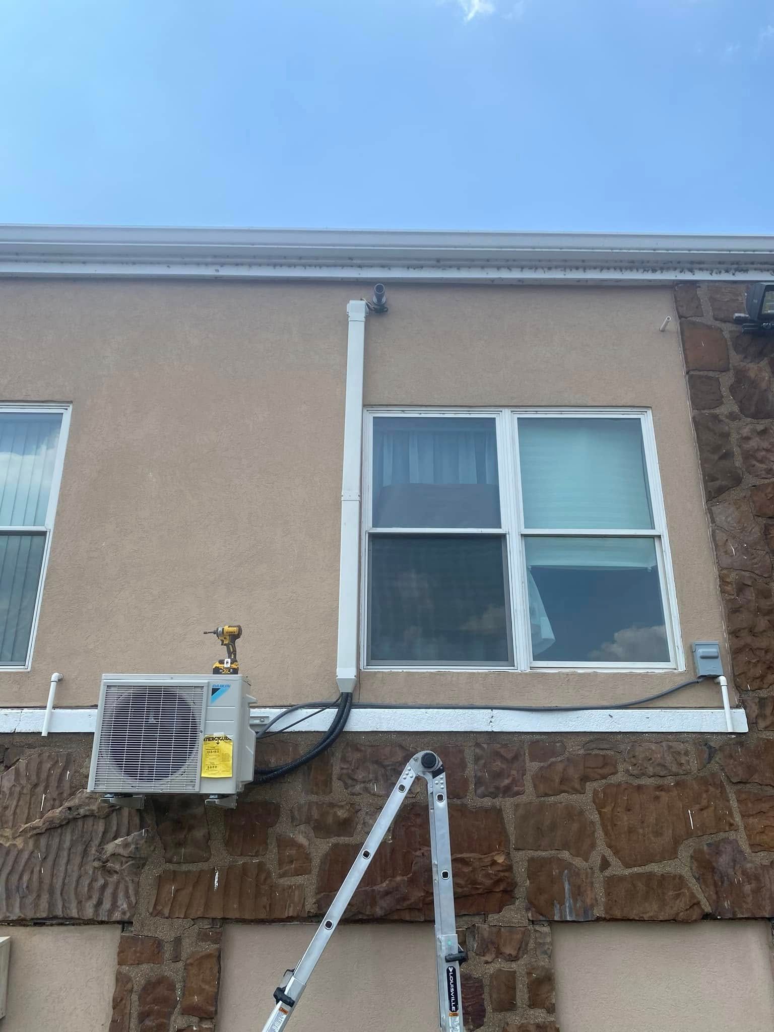A ladder is sitting on the side of a building next to a window.