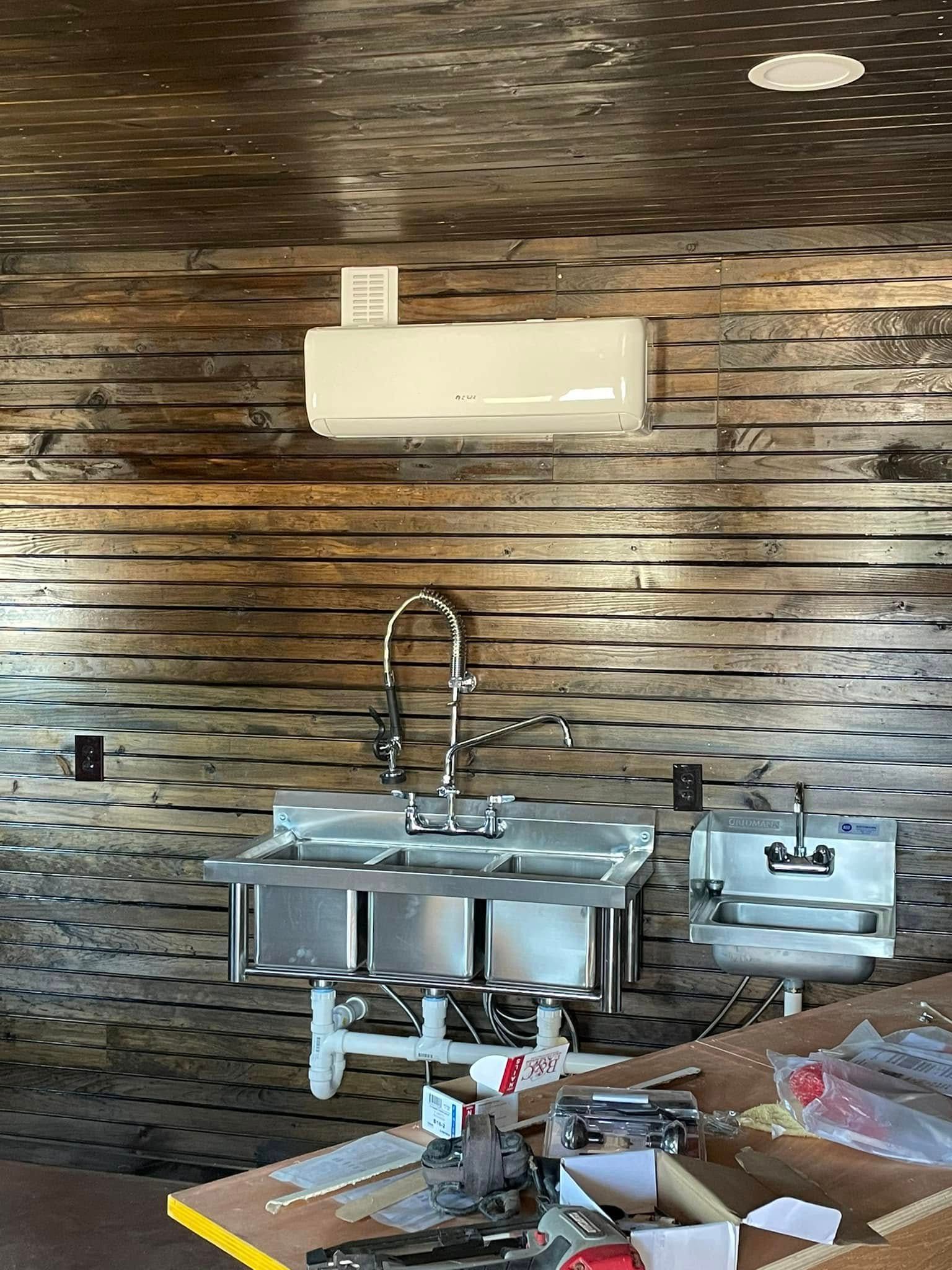 A kitchen with a stainless steel sink and a wooden wall.