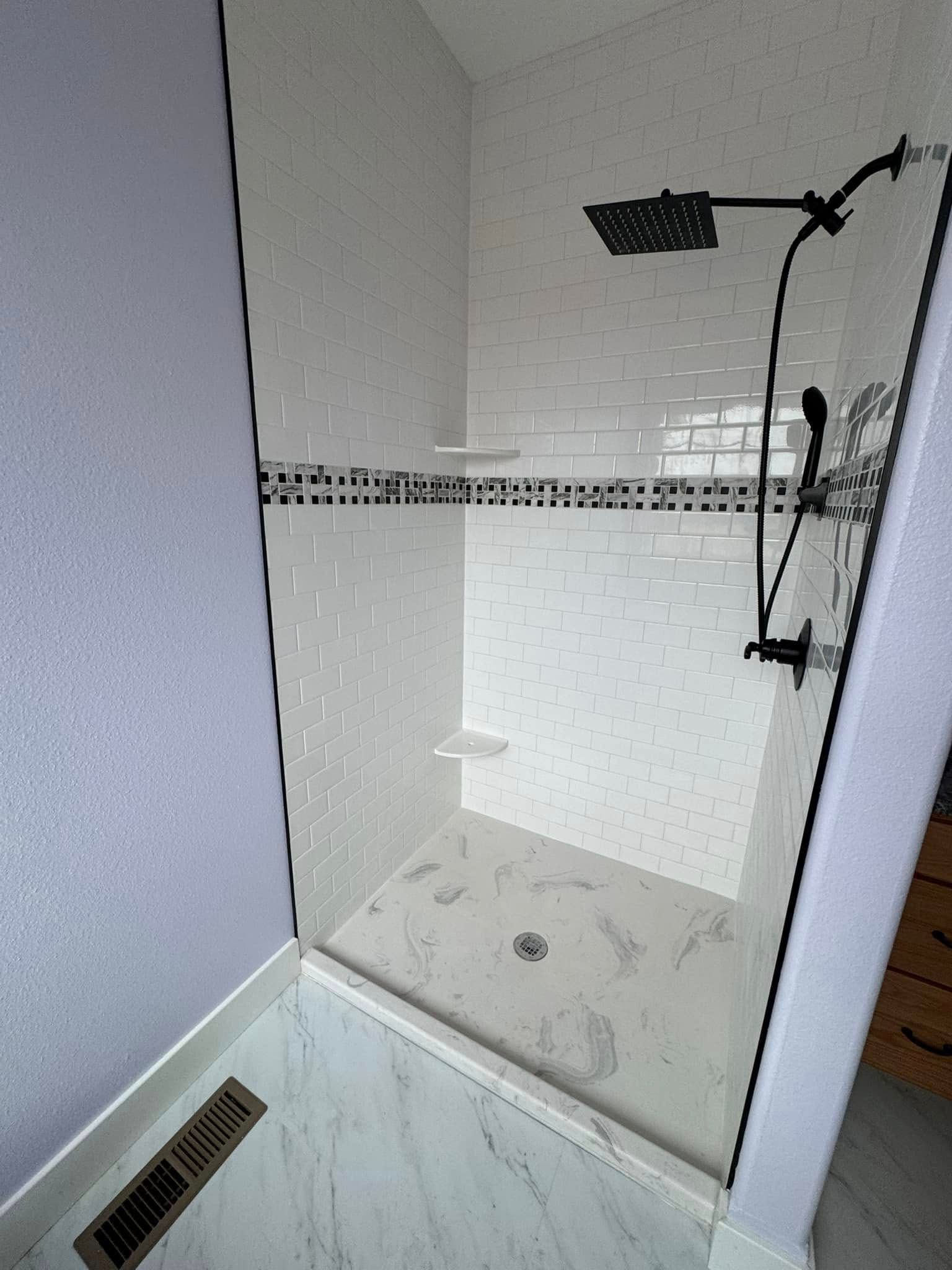 A bathroom with a walk in shower and a black shower head.