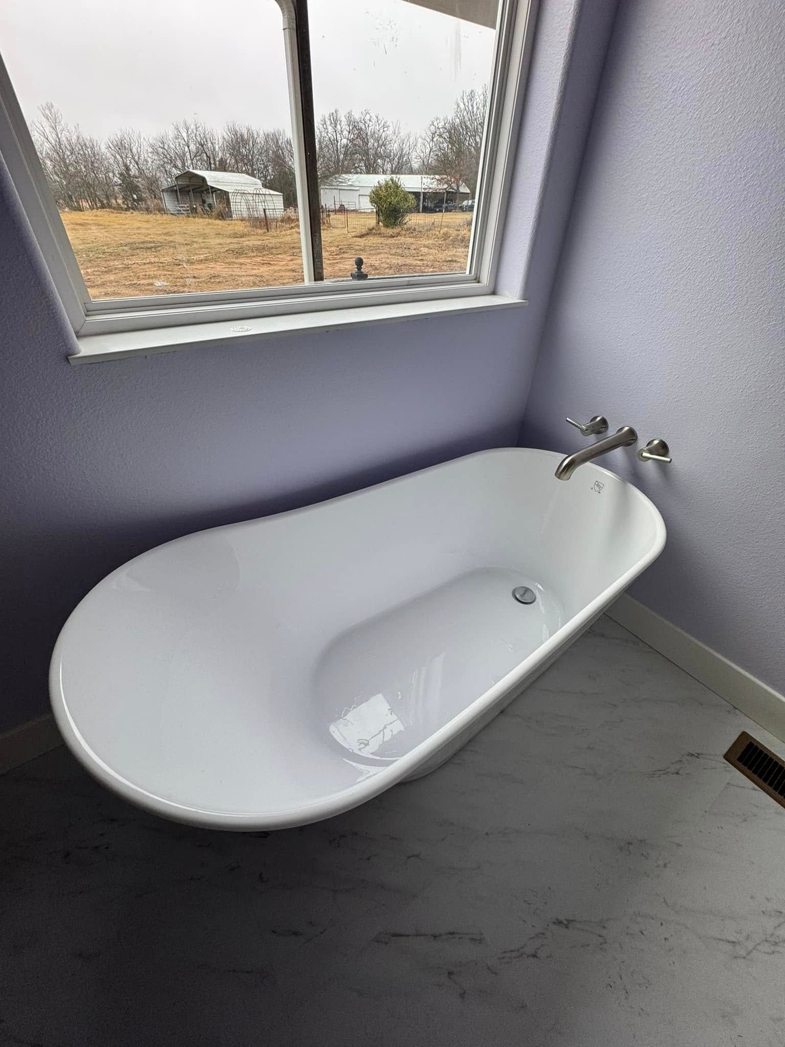 A white bathtub is sitting in a bathroom next to a window.