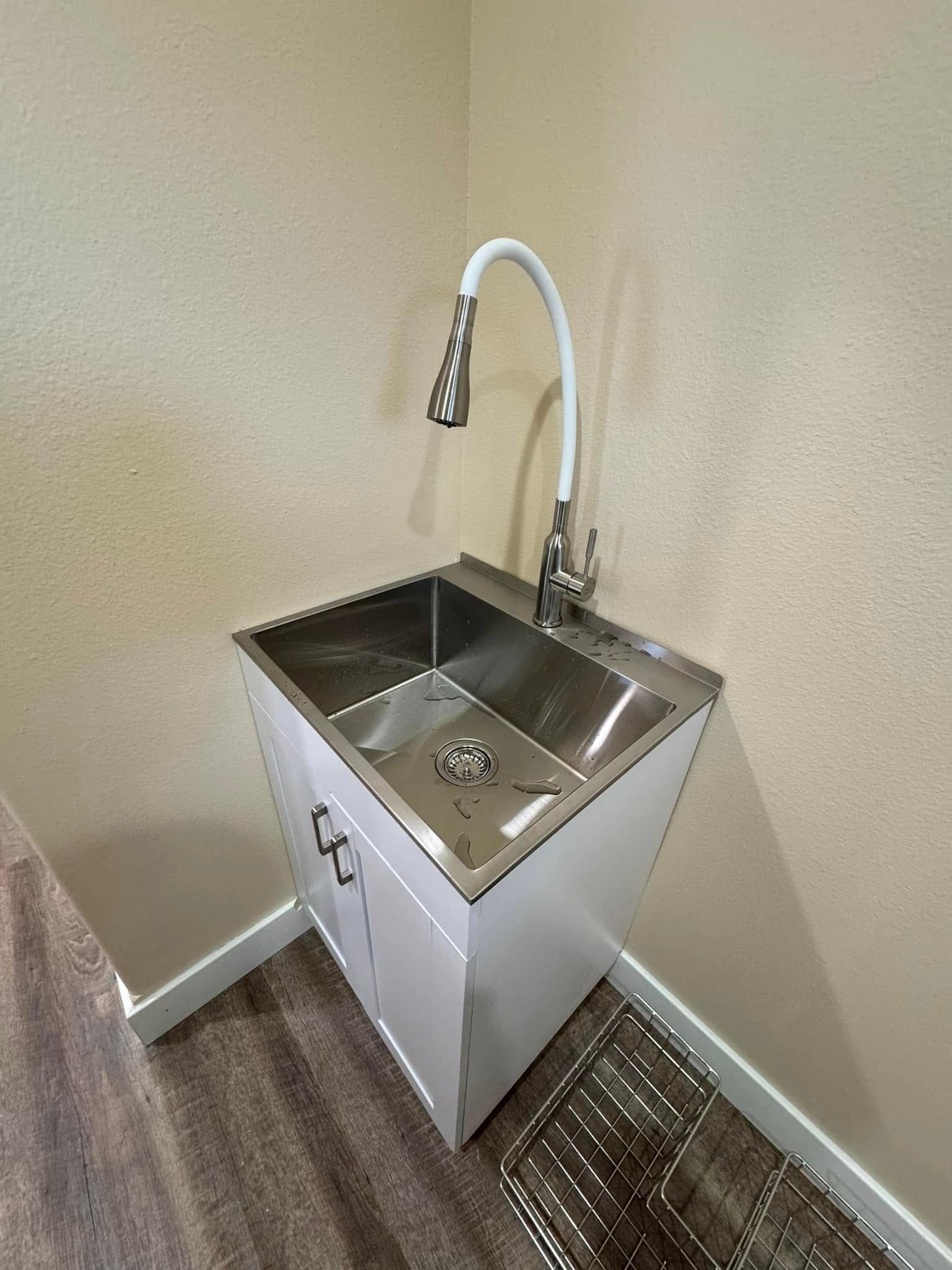 A stainless steel sink with a white faucet in a laundry room.