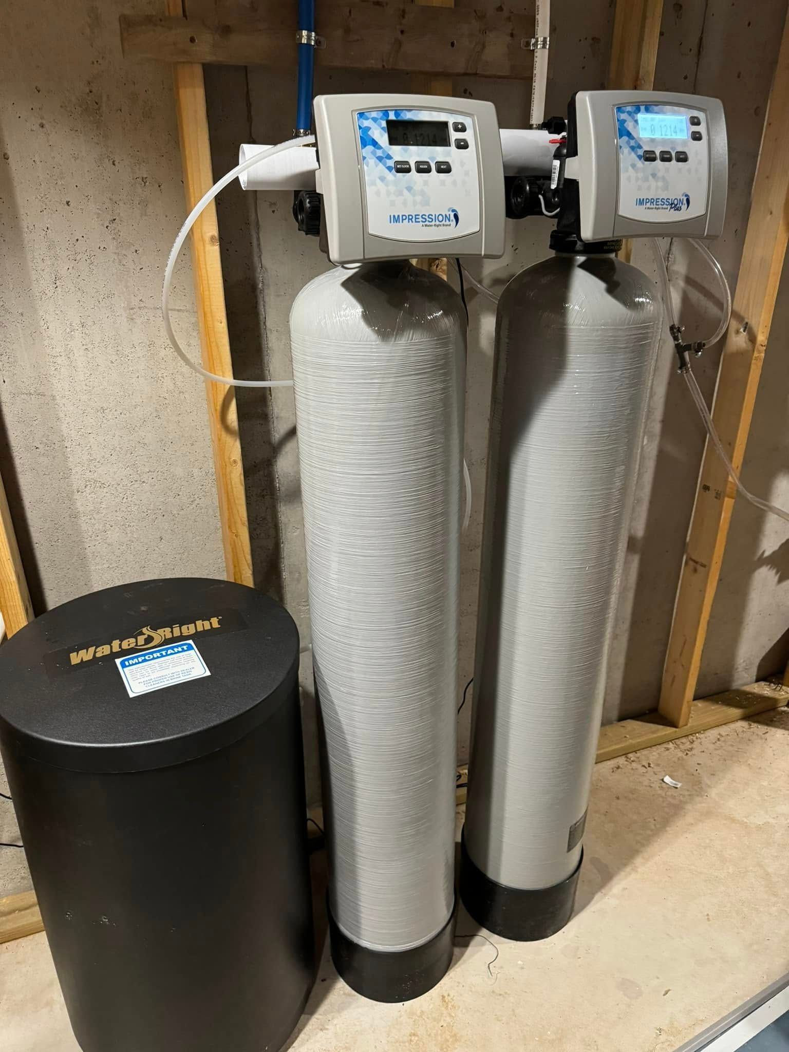 Two water filters are sitting next to each other in a basement.