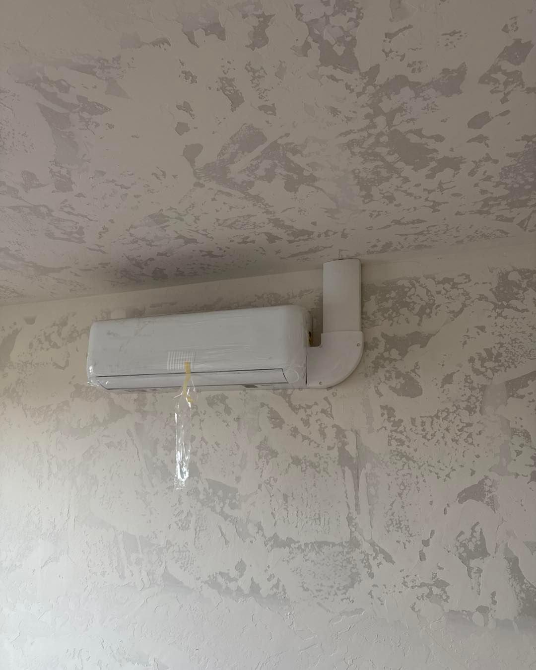 A white air conditioner is hanging from the ceiling in a room.