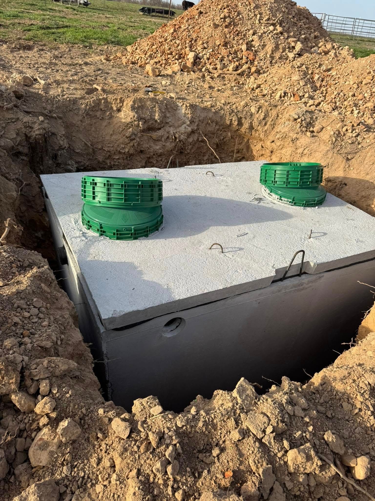 A septic tank is sitting in the middle of a dirt field.
