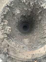 A close up of a dirty drain with a hole in the middle.