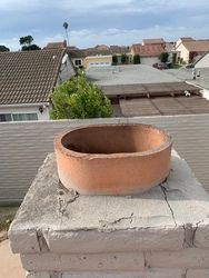 A chimney with a hole in it is sitting on top of a brick chimney.