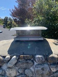 A chimney is sitting on top of a stone wall.