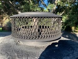 A fire pit is sitting on top of a rock in the woods.