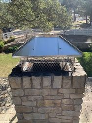 A brick chimney with a metal cover on top of it.