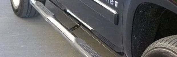Close-up of a dark SUV’s side step and lower door panel near the front wheel.