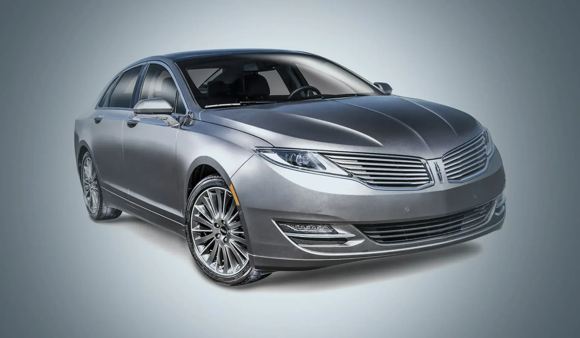 Silver luxury sedan on a studio background, shown in three-quarter front view.