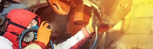 Rescue worker in red gear assisting inside a damaged vehicle, with bright emergency lights