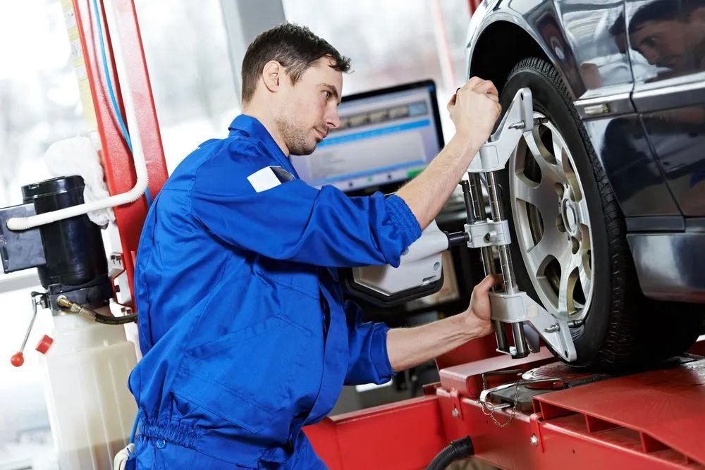 Mechanic in Blue Jumpsuit Adjusts Wheel Alignment — Wheel Alignment Centre in Braitling, NT
