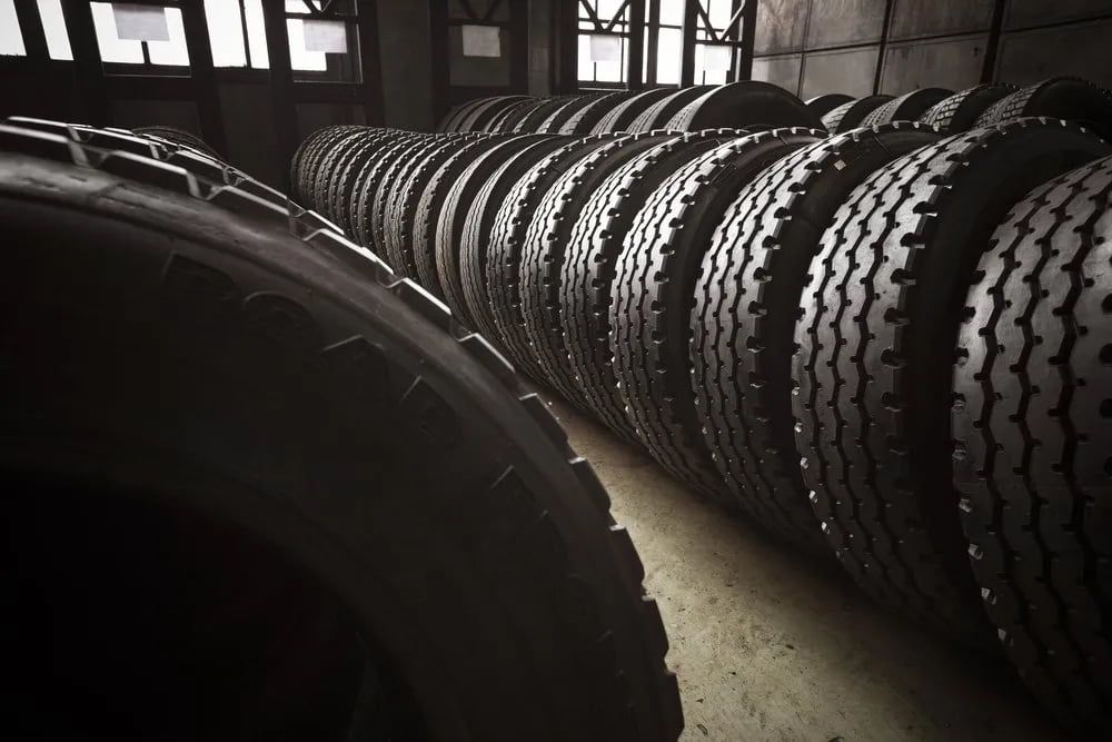 Row of Black Tires Stacked in a Dimly Lit Warehouse — Wheel Alignment Centre in Braitling, NT