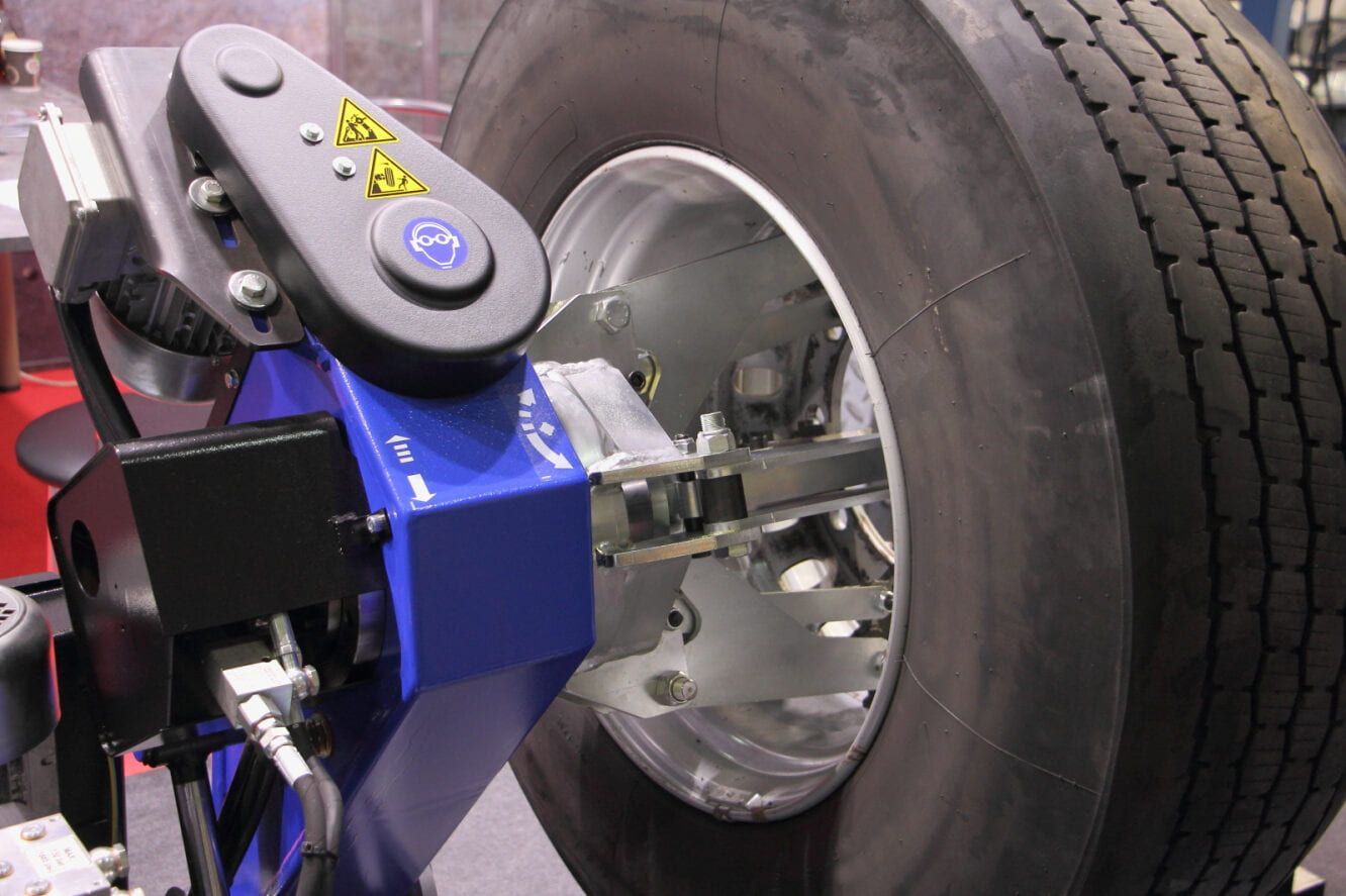 A Tire Mounted on a Machine, With a Blue and Black Arm Adjusting the Wheel — Wheel Alignment Centre in Braitling, NT