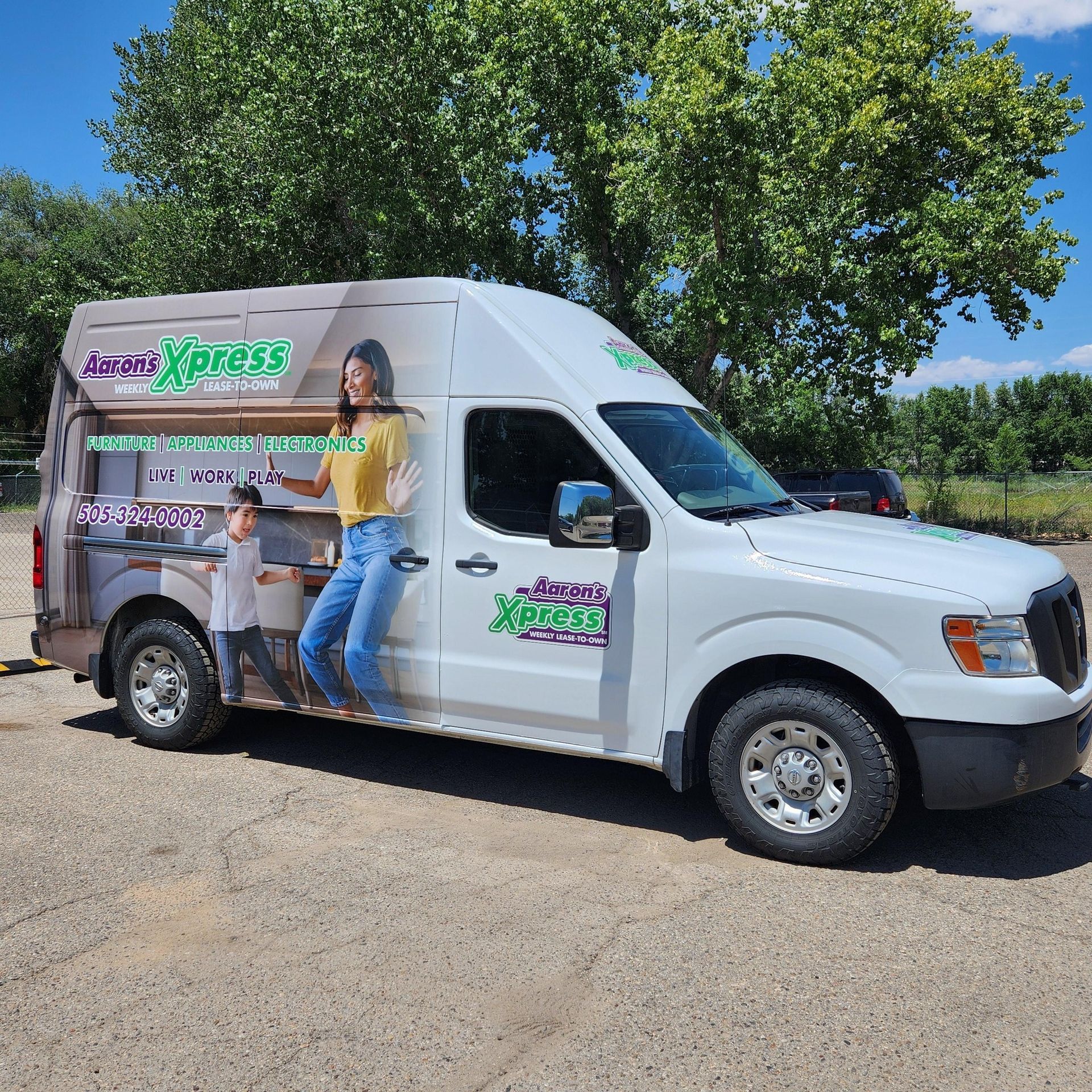 A white van with a picture of a woman and a boy on the side is parked in a parking lot.