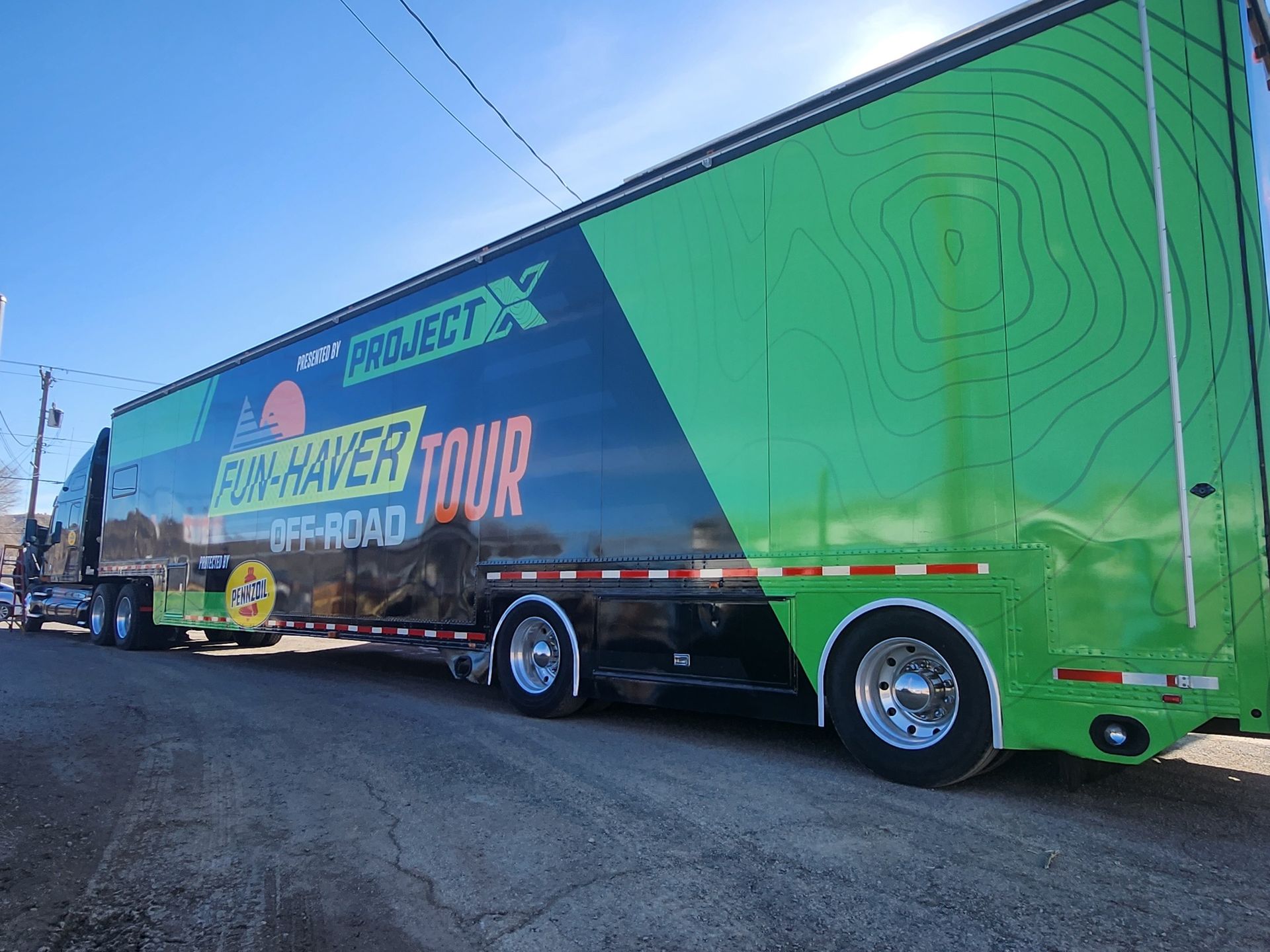A green and black trailer is parked on the side of the road.