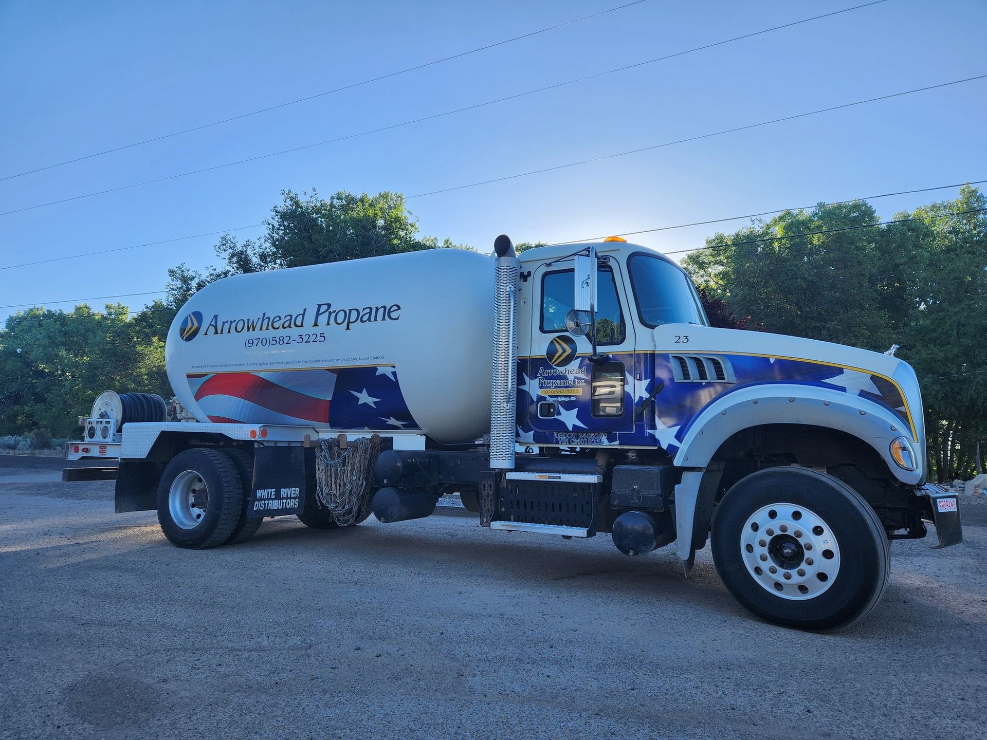 A propane truck is parked in a gravel lot.
