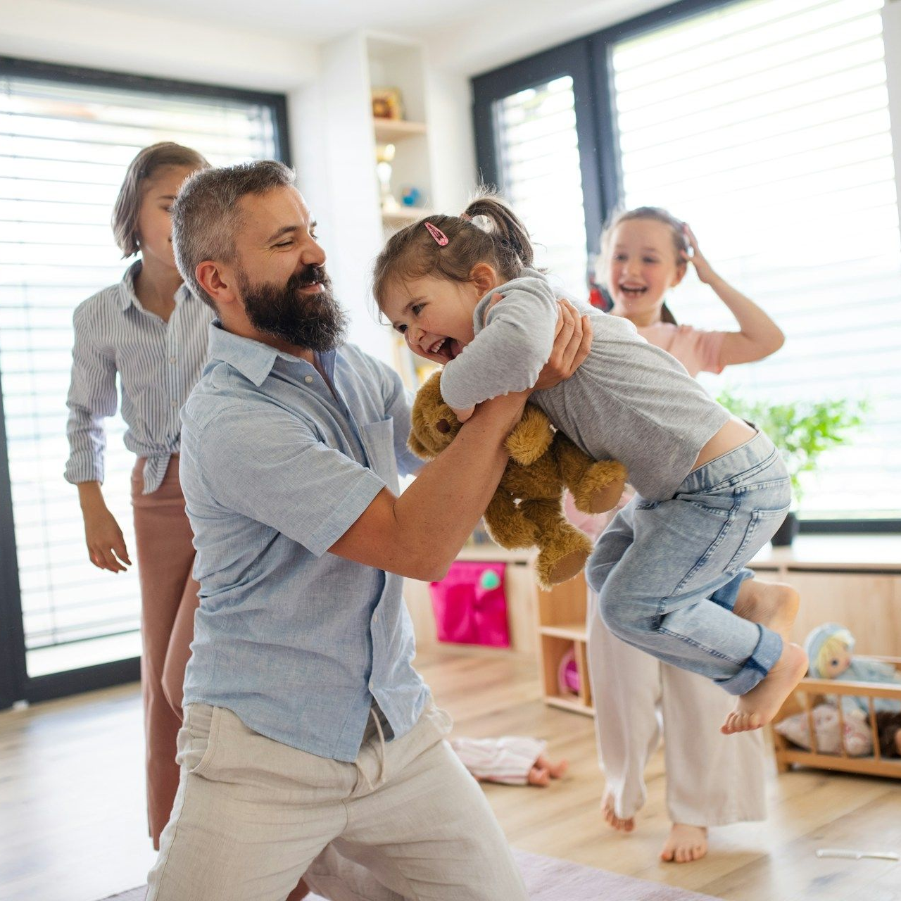 Grandparents hugging and kissing a young child indoors. They're smiling and laughing.