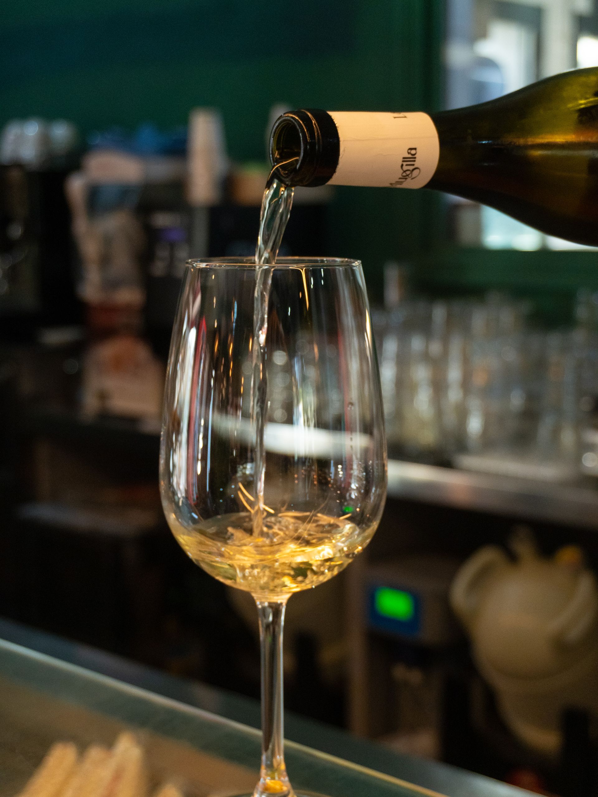 Vino bianco versato in un bicchiere alto al bar