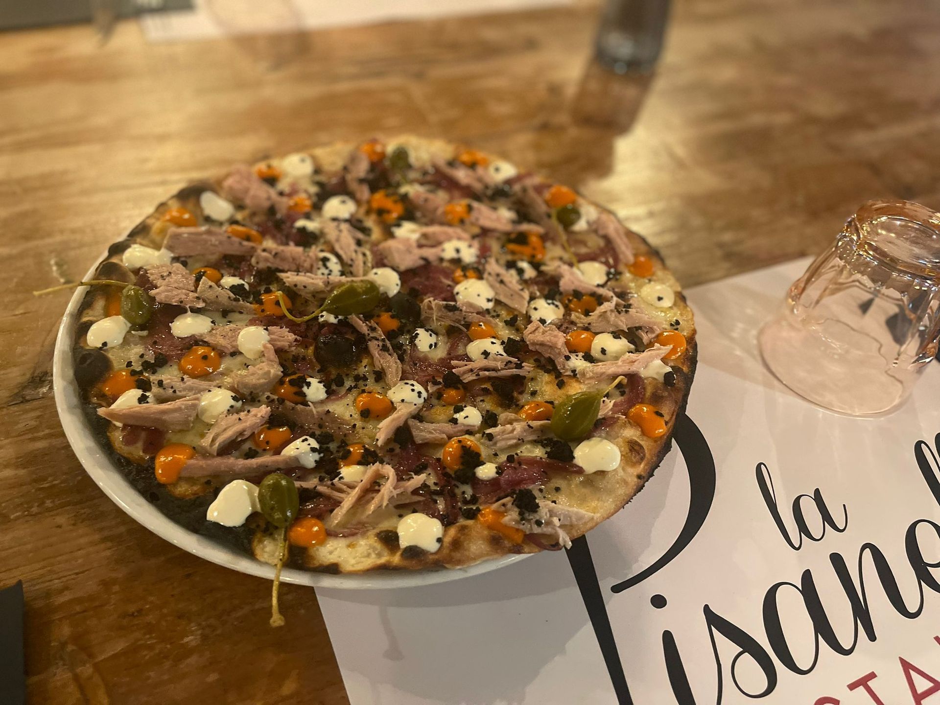 Persona che tiene in mano un piatto bianco di pasta con una forchetta, all'aperto, vicino alle piante.